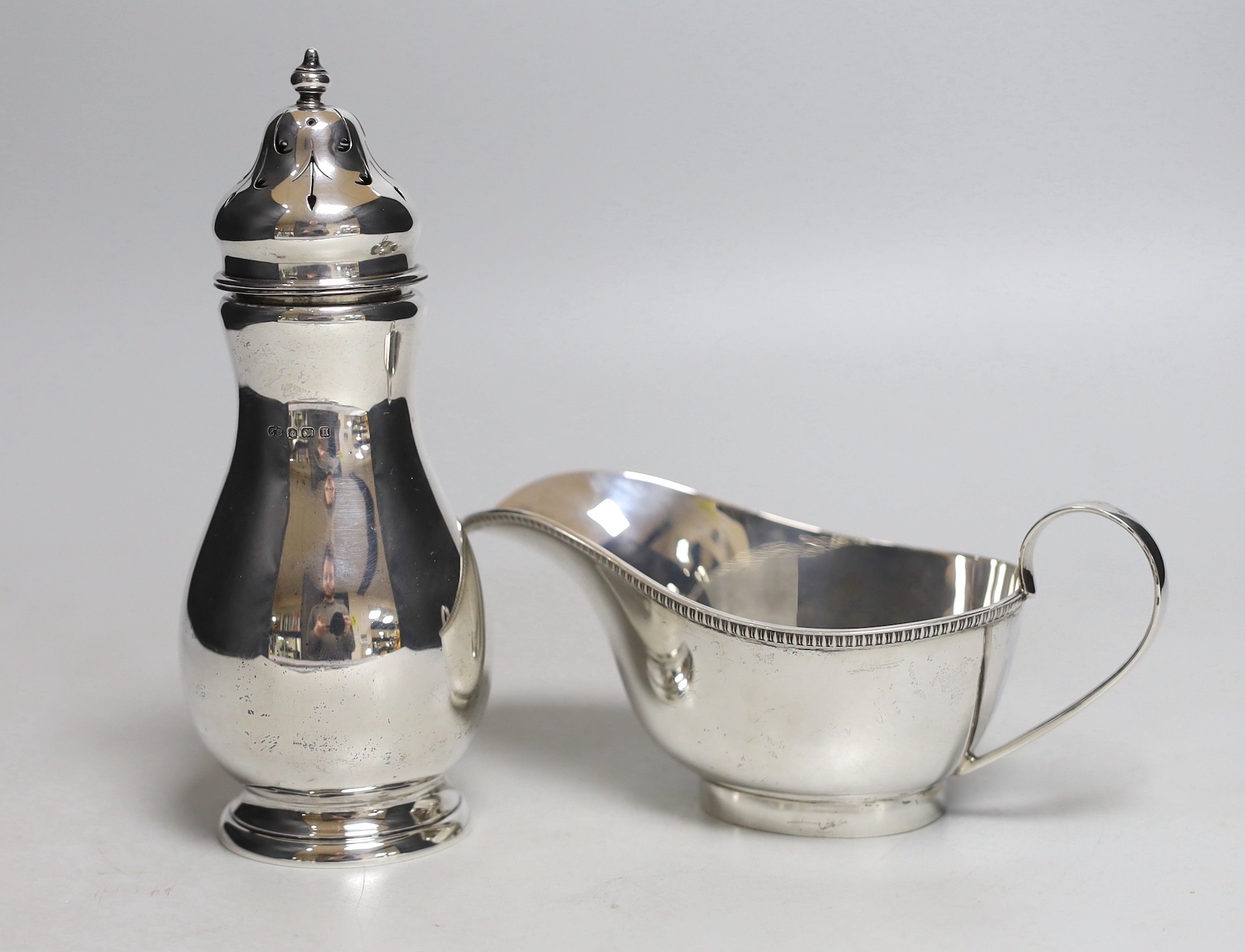 A George V silver sugar caster, Birmingham, 1932, 16.8cm and a silver sauce boat, 10.2oz.